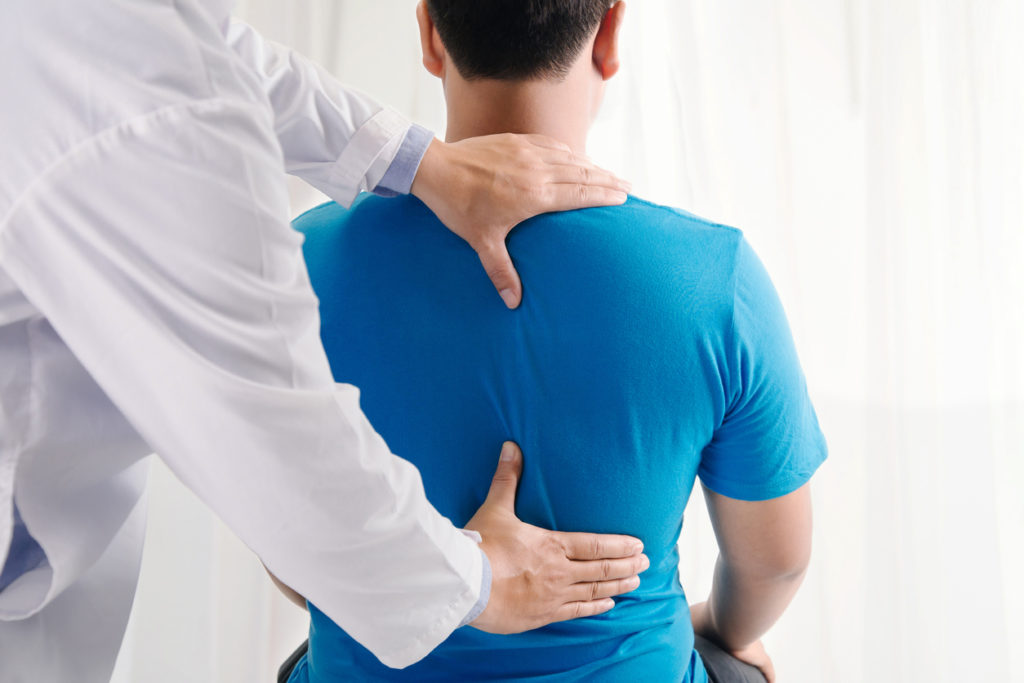 Chiropractor examining a man's back pain