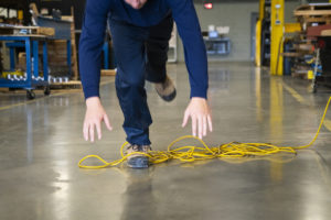 A worker tripping over an electrical cord in an industrial environment