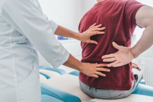 chiropractor examining patient's back in clinic